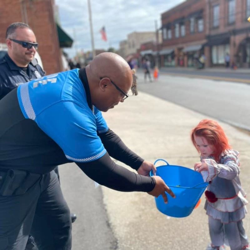 Clayton Police Hand out Candy to Child during Trick-or-Treat Main Street