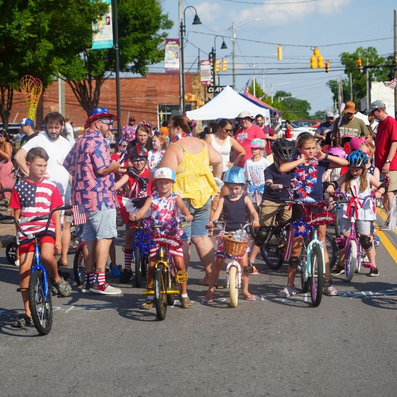 Kids in patriotic attire sit on bikes on Main Street waiting for bike parade to start