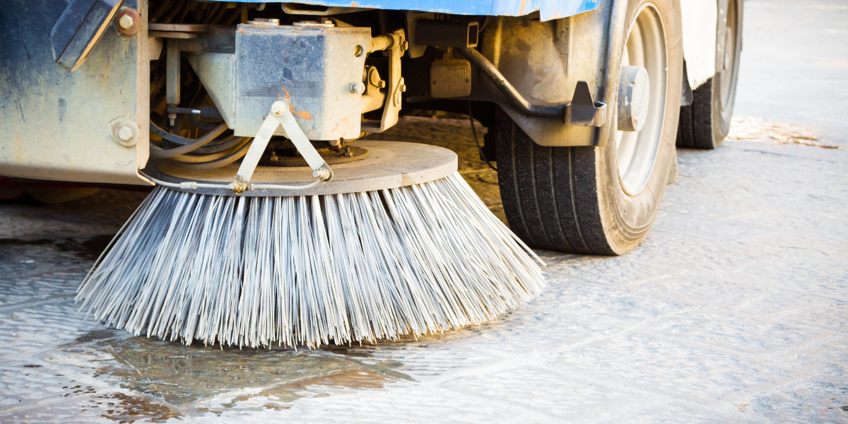 Close up on street cleaning truck brush cleaning wet street